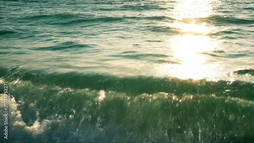 Golden sunlight reflects on the calm turquoise ocean waves