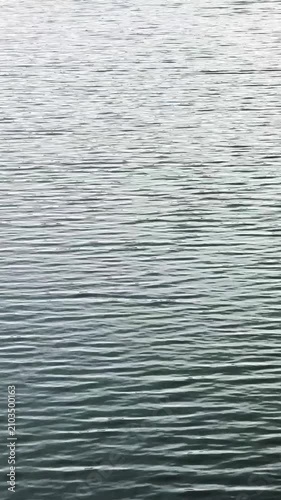 静かな光の中で細かく波打つダークトーンの落ち着いた水面のクローズアップ動画素材