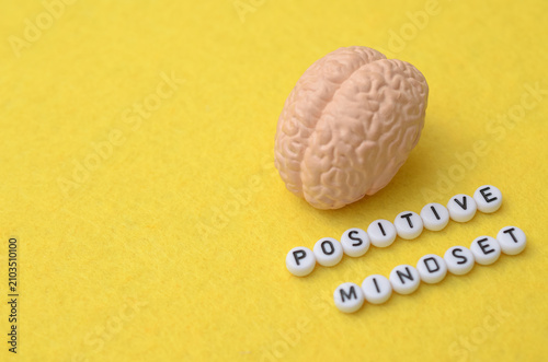 Konstfotografi Positive Mindset text spelled in letter beads with human brain model on yellow background