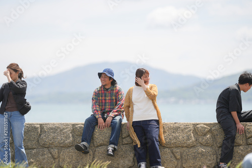 Cuadro en lienzo Four people relax on a stone wall by the sea