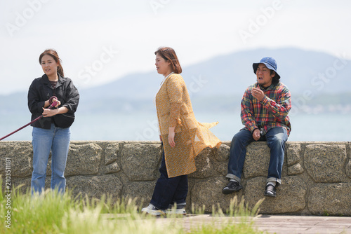 Foto Three people relax on a seaside wall