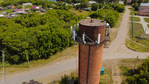Canvastavla drone photograph showing a historic red brick water tower repurposed as a cell t