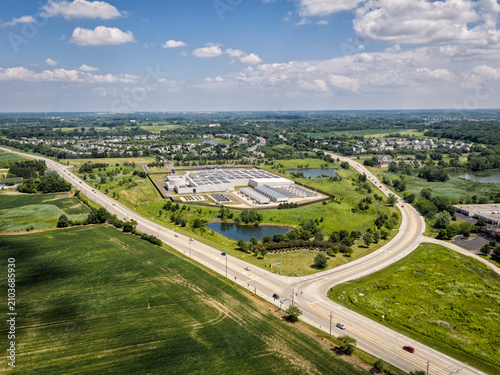 Aerial view of a modern data center facility with solar panels on the roof, cooling units and server buildings