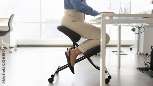 Tableau sur toile Lower body part of office employee seated at desk on ergonomic chair, working on