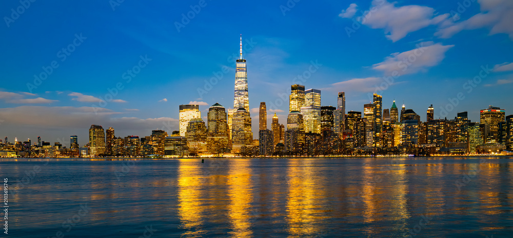 Fototapeta premium New York waterfront skyline at dusk. New York illuminated towers reflected. New York Manhattan evening panorama. New York riverfront cityscape.