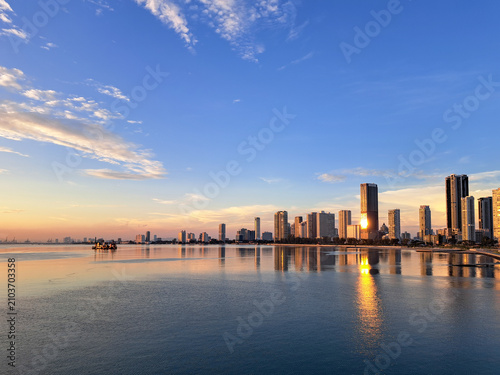 Fotografia The sky glows a soft orange over the calm waters