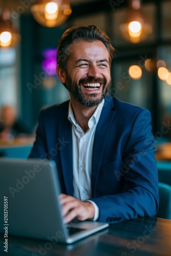 Businessman Works on Laptop and Smiles in Modern Office Space