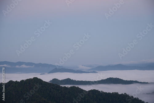 Breathtaking aerial view of misty valleys and lush green tropical rainforest mountains at dawn
