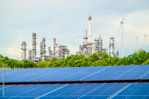Bild auf Leinwand Solar panels with petrochemical oil refinery factory in background