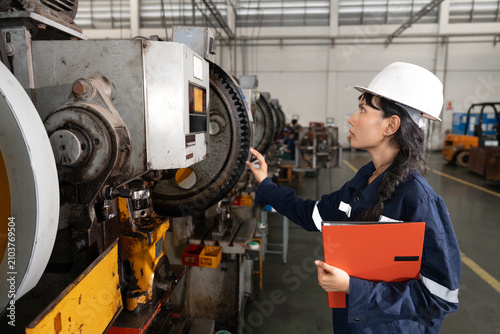 Female factory worker inspecting machinery in industrial plant