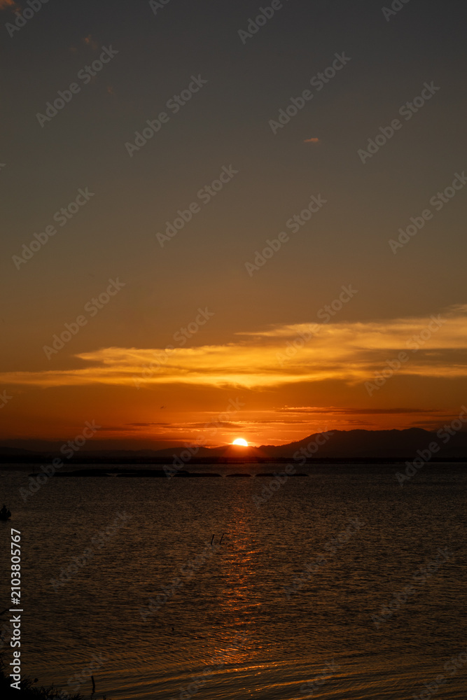 Fototapeta premium Sunset Over Water With Mountain Silhouette