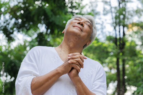 Foto Relaxed happy refreshing old retired senior Asian man taking a deep breath of cl