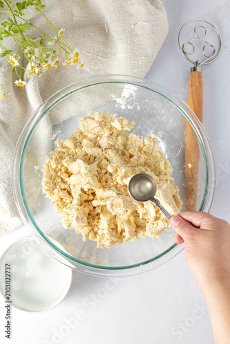 A hand adding water to crumbly pastry dough