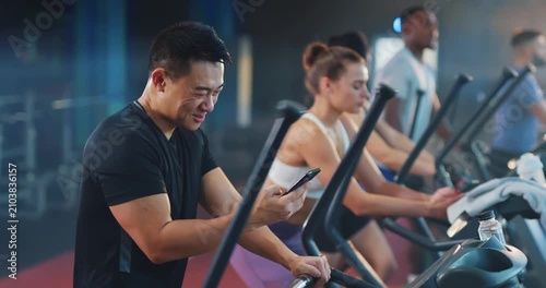 Fitness enthusiasts work out at a modern gym, tracking their progress on their phones