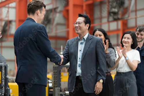 Group of male and female workers and manager standing discussing, meeting together in factory. Diverse corporate colleagues and multicultural in factory