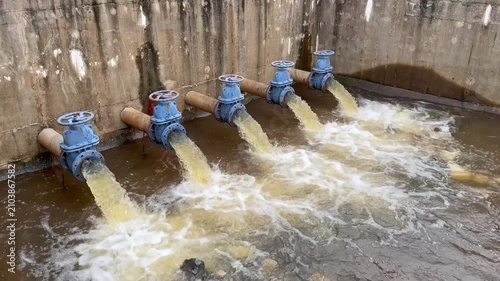 Academic engineering footage demonstrating industrial water drainage infrastructure. Video showcases large pipeline gate valves discharging liquid flow for flood management lesson