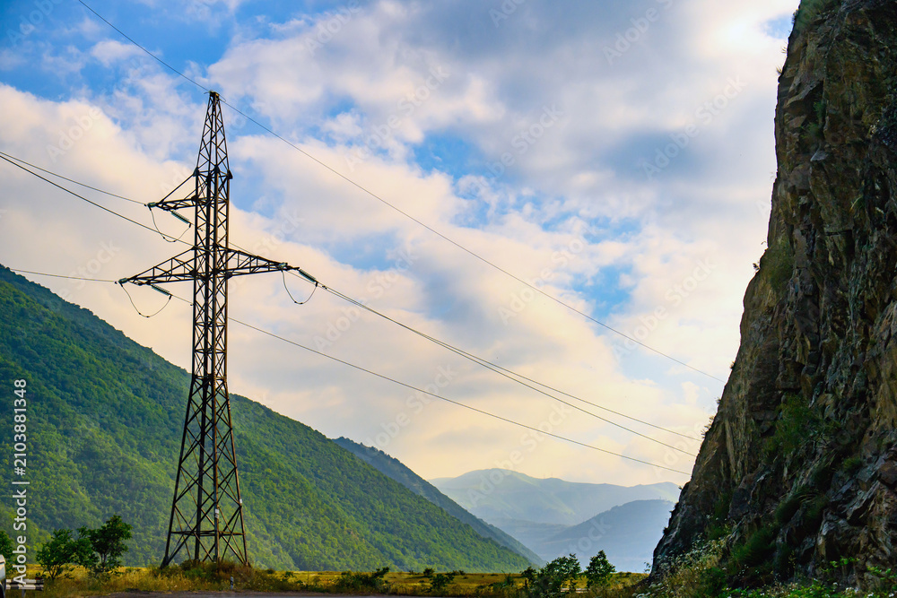Obraz premium High voltage transmission tower near mountainous terrain