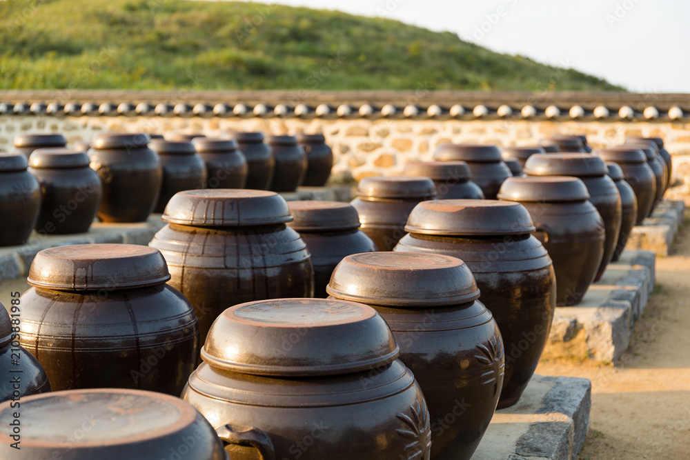 Obraz premium Rows of traditional Korean onggi jars on a stone platform at sunrise