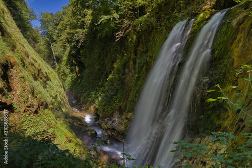 Принти на полотні Gran cascada en un desfiladero boscoso con vegetación frondosa en los Pirineos