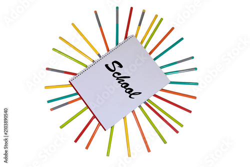 Blank white spiral notebook sits in the center surrounded by many colorful pencils arranged in a bright circular sunburst pattern.