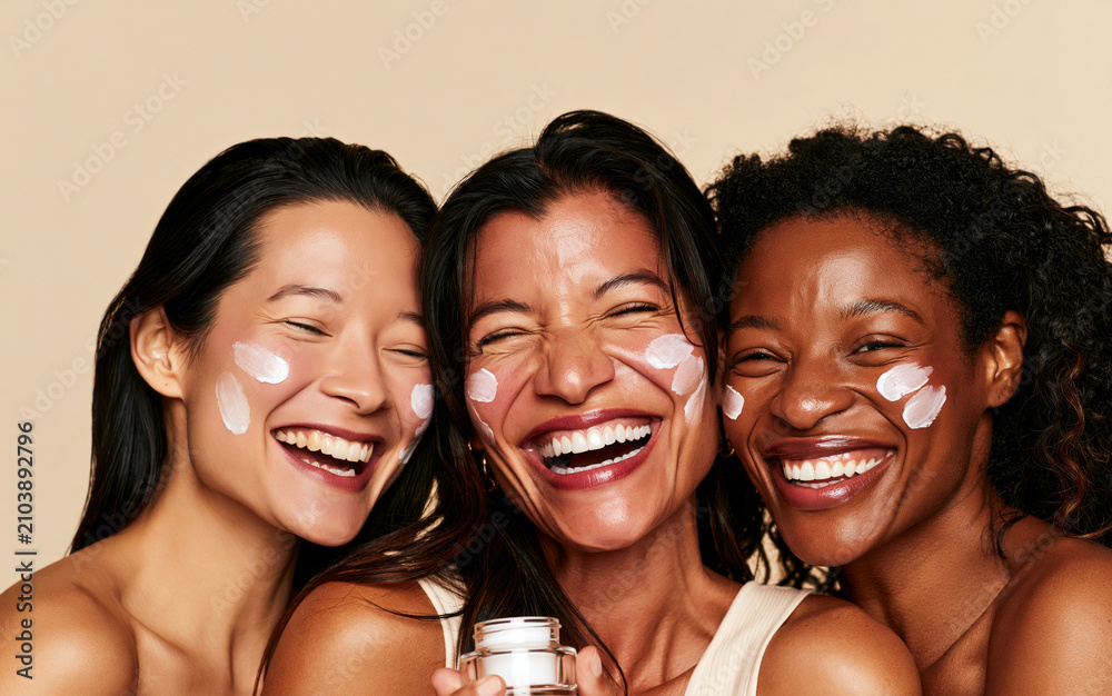 Obraz premium diverse women laughing and smiling, showcasing glowing natural skin with white skincare cream 