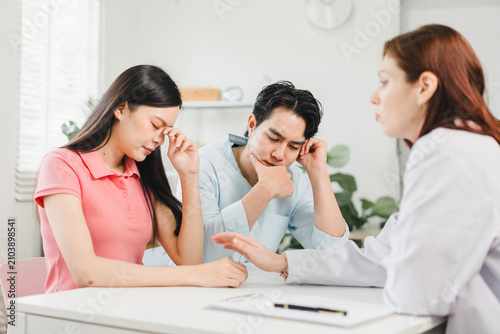 Stressed couple having a consultation with a professional doctor in a bright clinical office
