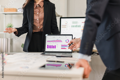 Professional business colleagues analyzing data trends on laptop screens during a meeting in office