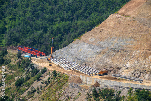 Canvas Print Highway construction in mountainous terrain with heavy machinery