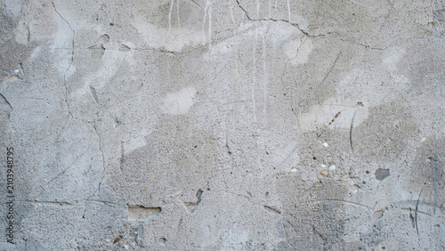 Weathered gray concrete wall surface with fine cracks, stains, and rough texture, close-up view of industrial building exterior