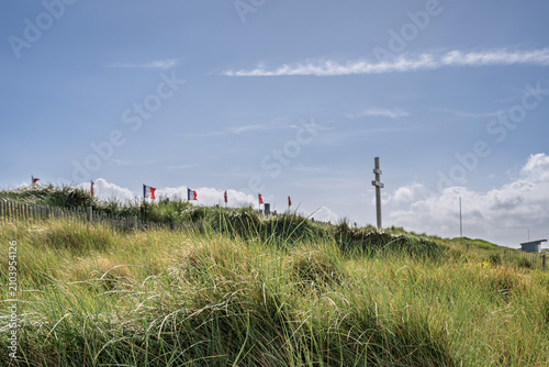 Foto French flags and the Cross of Lorraine monument on a grassy hill overlooking the sandy shore of Juno Beach in Courseulles-sur-Mer Normandy France historic WW2 site