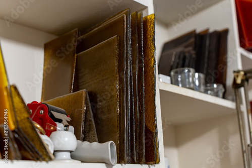Foto Sheets of brown and yellow glass for vitreous hot enamel or stained glass art standing on a storage shelf inside a creative craft workshop workspace
