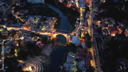 Mostar, Bosnia and Herzegovina - June 7, 2026: Drone moving right above the illuminated Old Bridge overlooking the Neretva River