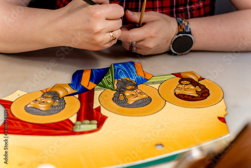Foto Close up of artist hands painting religious icon figures on a metal plate using hot vitreous enamel technique on a studio workbench