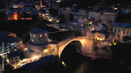 Mostar, Bosnia and Herzegovina - June 7, 2026: High aerial approach toward the illuminated Old Bridge overlooking the Neretva River