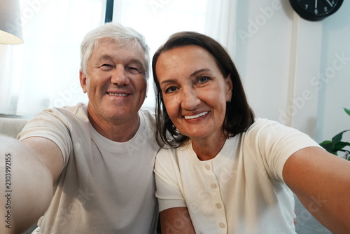 Foto The grandparents are holding their smartphones, taking selfies and smiling at the camera together