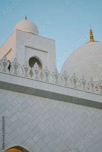 Obraz na plátně White marble mosque domes and ornately carved arabesque parapet detail against a