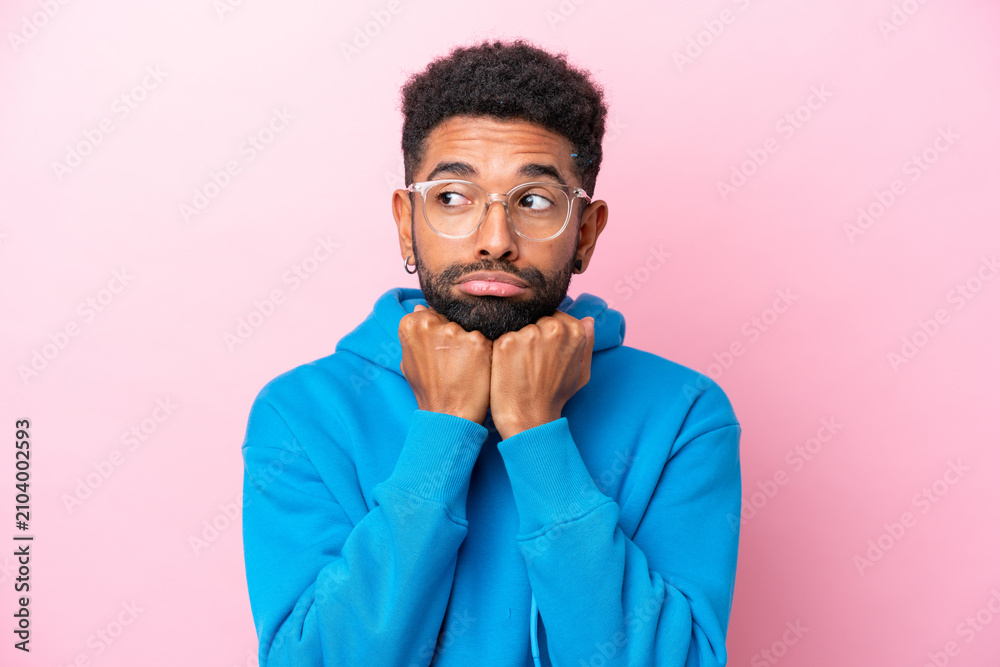 Obraz premium Young Brazilian man isolated on pink background With glasses and tired