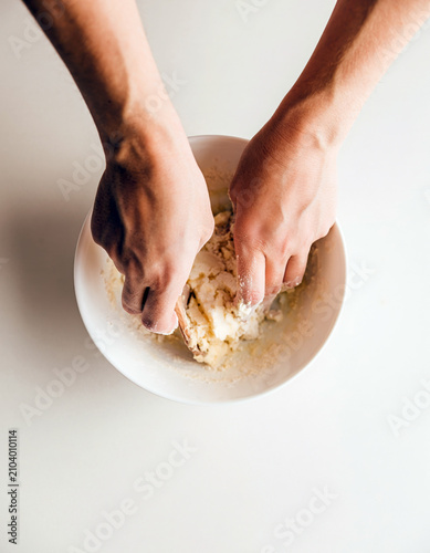 Hands mixing flour in a bowl for homemade dough, simple baking preparation with natural ingredients and copy space