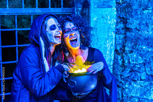 Fotografie Two women celebrating halloween wearing spooky makeup and witch costumes