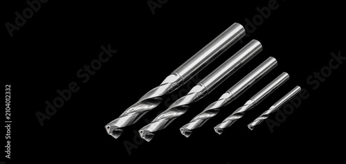 Solid carbide twist drills with through coolant holes isolated on a black background. Precision CNC cutting tools for metal drilling, machining, manufacturing, engineering, and industrial production.