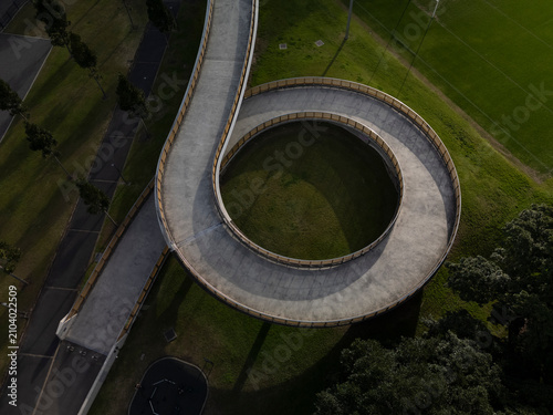 Large spiral bridge aerial view carrying pedestrians, cyclists and joggers. Bridge in beautiful afternoon light