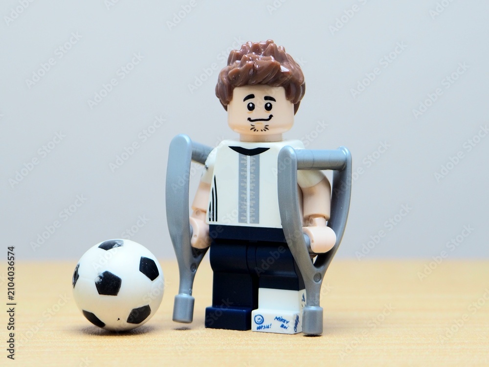 Fototapeta premium Indonesia - May 27, 2026 : Mini toy of action figure at outdoor with blur background. Miniature photography concept design. Minifigure of Injured people on crutches. Athlete character with broken leg.