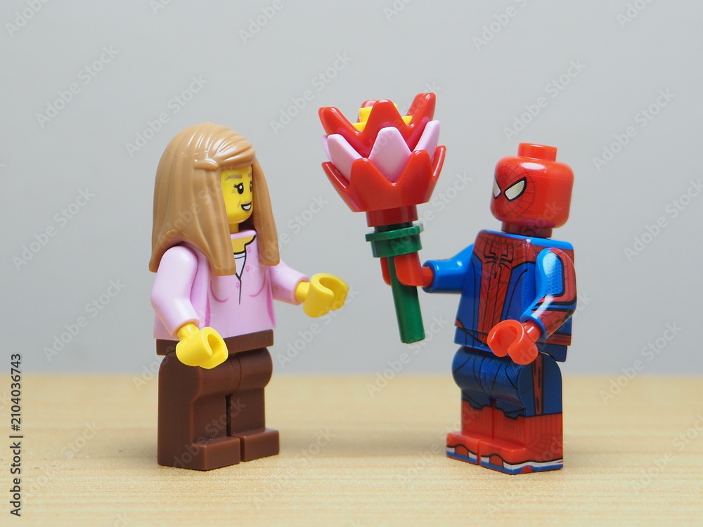 Naklejka premium Indonesia - May 27, 2026 : Mini toy of action figure at outdoor with blur background. Miniature photography concept design. Minifigure of man character give bouquet of flower to young girl. Romantic.