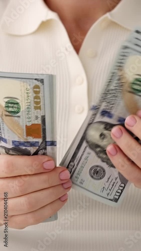 Woman hands counting hundred US dollar bills close up vertical format, female holding stack of 100 USD cash banknotes, financial business success wealth investment background