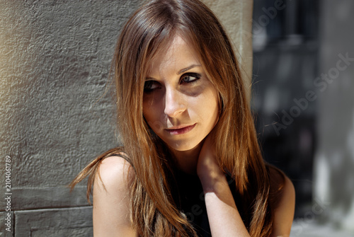 Fotografie Pensive young woman leaning against textured wall outdoors, bathed in natural light