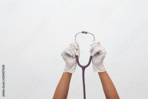 Obraz na plátne Doctor's hands in white gloves holding a stethoscope against a white background