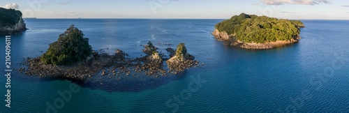 Scenic view of iDonut sland in the ocean near Whangamata, New Zealand.. The islands are covered in lush green trees and surrounded by deep blue water.