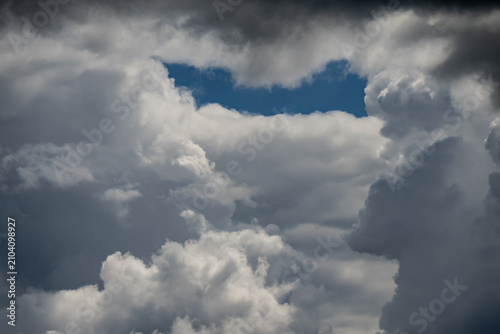 Bild auf Leinwand Fluffy white cumulus and dark dramatic storm clouds gathering in the atmosphere
