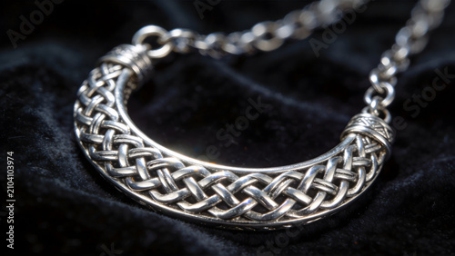 Close-up of intricate Celtic silver knotwork jewelry on dark velvet.