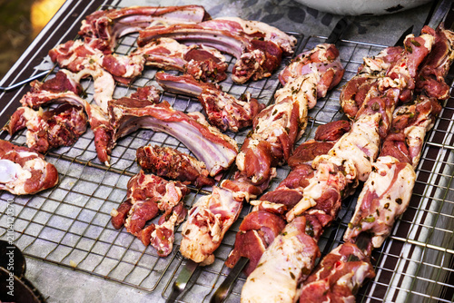 Raw lamb ribs and pieces of meat laid out on a metal grill before cooking. Fresh lamb with a natural texture is ideal for cooking shish kebab, barbecue, grill and traditional meat dishes. The photo
